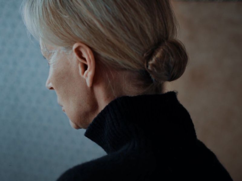 žena starijih godina gleda kroz prozor sa prelepom punđom za kratku kosu