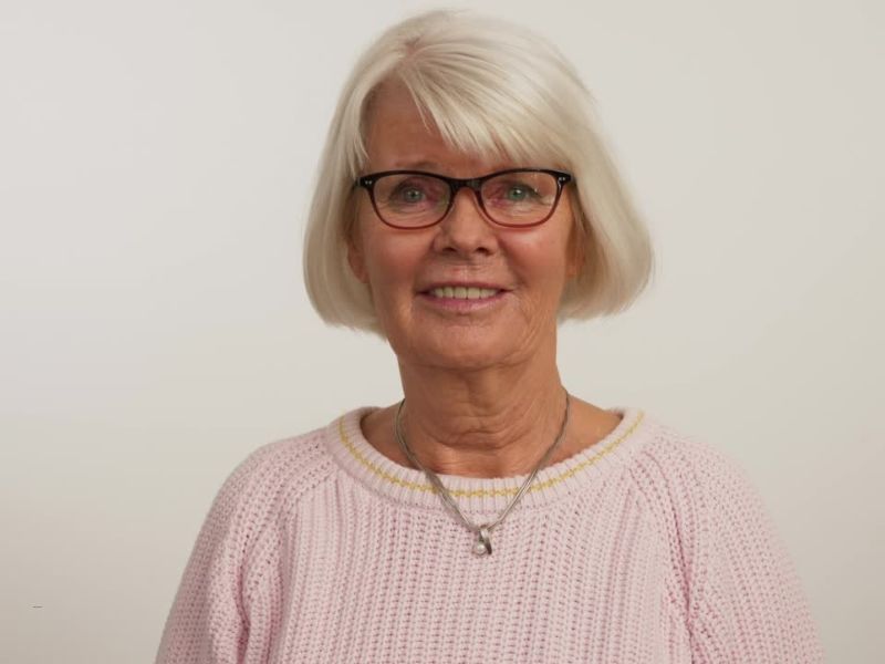 žena sede kose sa kratkom paž frizurom se smeši sa naočarima na licu